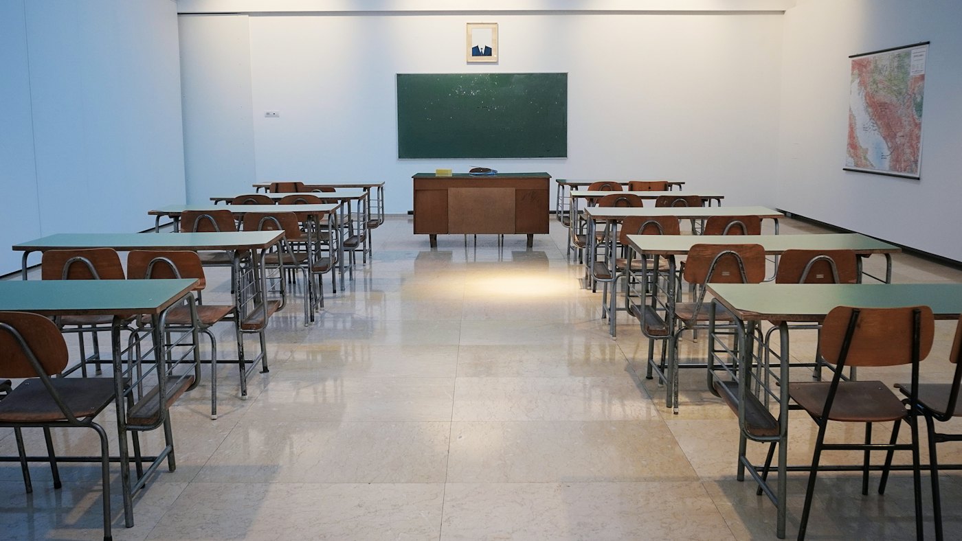 Bilik darjah dengan papan hijau dan meja kosong